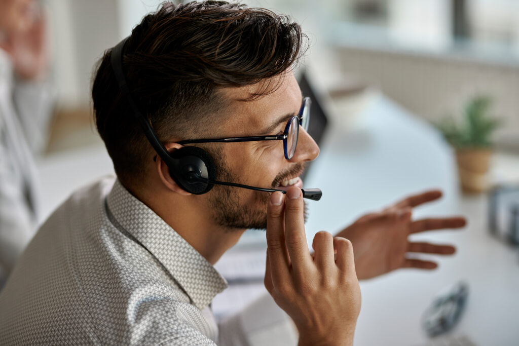 happy call center agent wearing headset while talking with clients working office